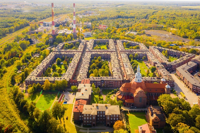 Widok z lotu ptaka na starannie zagospodarowaną dzielnicę mieszkaniową z budynkami o czerwonych dachach i terenami zielonymi znajdującą się na katowickim Nikiszowcu.